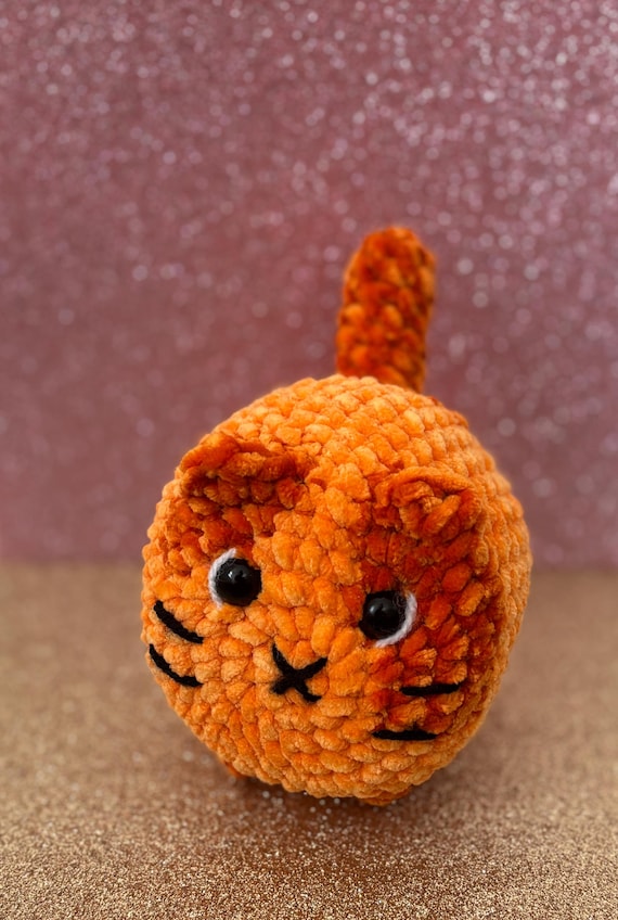A cat squished into loaf-position, crocheted by hand — the amigurumi format nails the internet's favorite cat meme in tactile, desk-worthy form.
