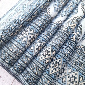May include: A blue and white patterned rug with a geometric design. The rug is folded in half and the edges are visible.