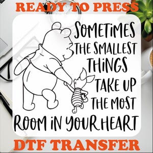 May include: Black and white illustration of Winnie the Pooh and Piglet with the quote "Sometimes the smallest things take up the most room in your heart".  The image is ready to be pressed onto a t-shirt or other fabric using a DTF transfer.