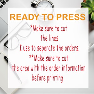 May include: White paper with orange text that reads "READY TO PRESS." Below, red text instructs to cut lines and order information before printing. A laptop, glasses, and a clock are visible.