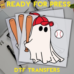 May include: DTF transfers featuring a cartoon ghost wearing a red baseball cap and holding a baseball bat. A baseball is also shown. The text "READY FOR PRESS" and "DTF TRANSFERS" are in yellow.