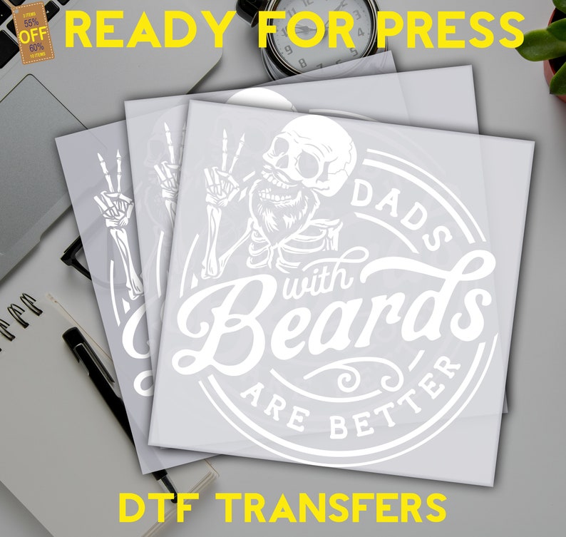 K&ouml;nnte beinhalten: Wei&szlig;e Vinylfolien mit einem Design eines Skeletts mit Bart und dem Text "Dads with Beards are Better" in einem Kreis. Der Text "DTF Transfers" befindet sich am unteren Rand des Bildes.