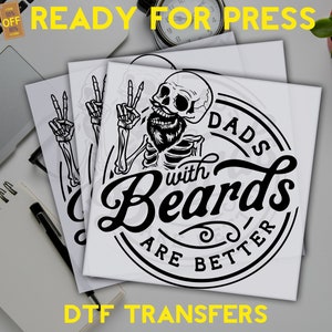 K&ouml;nnte beinhalten: Ein schwarz-wei&szlig;es Design eines Skeletts mit Bart und Peace-Zeichen, mit dem Text "Dads with Beards are Better" in einem Kreis darum herum. Das Design ist auf wei&szlig;em Hintergrund und bereit f&uuml;r den W&auml;rmetransfer auf ein T-Shirt oder einen anderen Stoff.