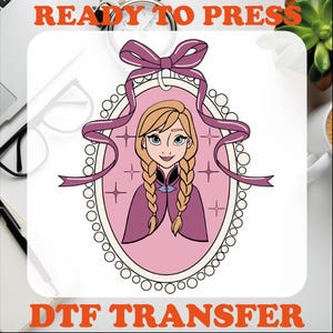 May include: A pink and purple DTF transfer design featuring a cartoon image of a girl with blonde braids wearing a purple cape and a pink dress. The girl is surrounded by stars and a pink ribbon bow. The text "READY TO PRESS" is at the top of the image and "DTF TRANSFER" is at the bottom.