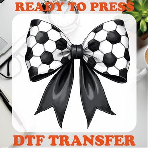 May include: A black bow with a white and black soccer ball pattern. The bow is ready to press for a DTF transfer.