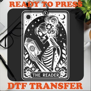 May include: Black and white illustration of a skeleton reading a book with the text "The Reader" on a white card with a black border. The card has a black star and crescent moon in the background. The card is labeled with an "R" in a circle in the top right corner.