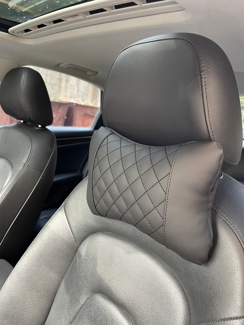 May include: Black leather car seat with a black quilted headrest pillow.
