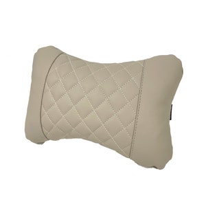 May include: A beige quilted pillow with a diamond pattern. The pillow is designed to provide support for the neck and head.