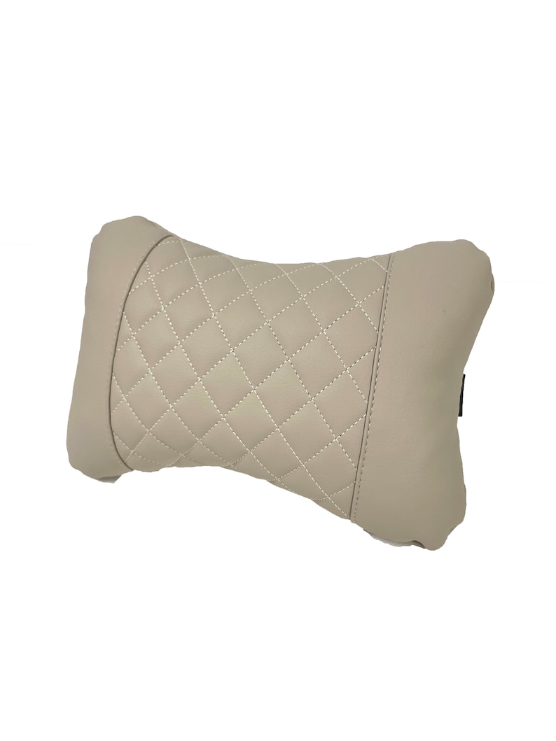 May include: A beige quilted pillow with a diamond pattern. The pillow is designed to provide support for the neck and head.