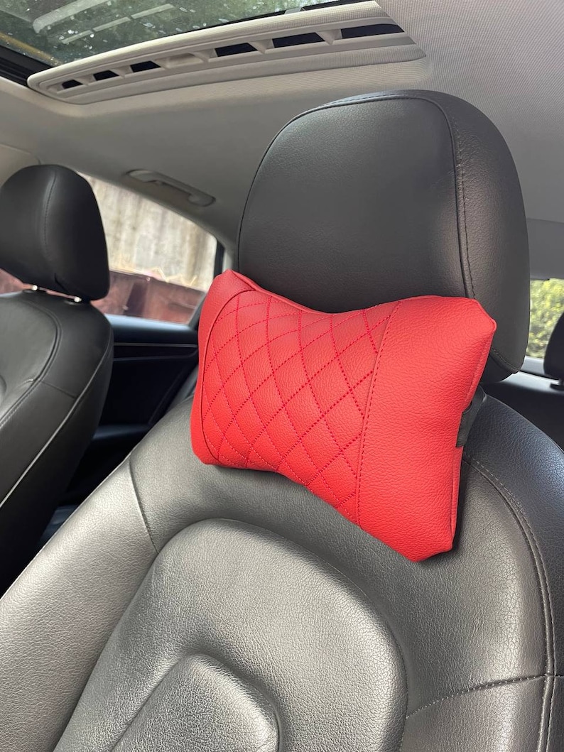 May include: Red quilted car headrest pillow. The pillow is designed to provide comfort and support for the head and neck while driving.