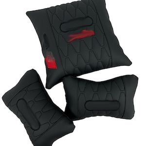 May include: Three black car seat cushions. The cushions have a geometric pattern and a red accent. The largest cushion has a red and white design. The cushions are designed to provide support and comfort.