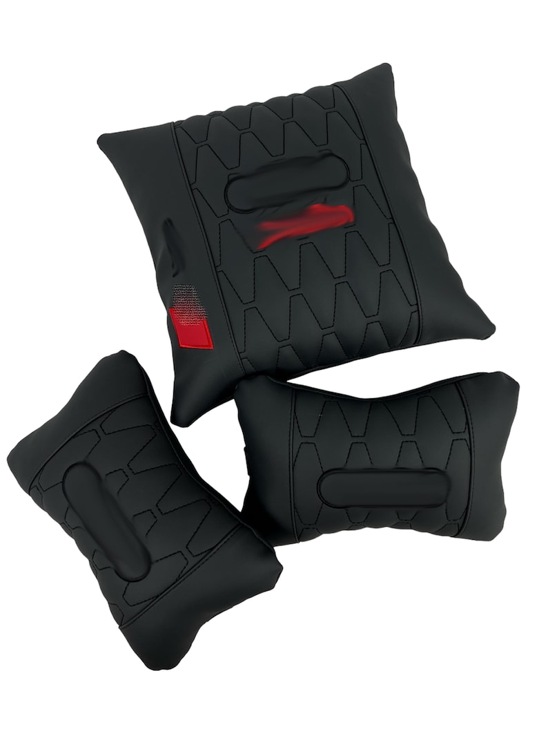 May include: Three black car seat cushions. The cushions have a geometric pattern and a red accent. The largest cushion has a red and white design. The cushions are designed to provide support and comfort.