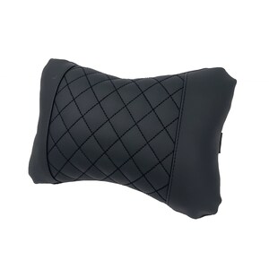 May include: Black quilted headrest pillow for car seats. The pillow is designed to provide comfort and support for the head and neck.