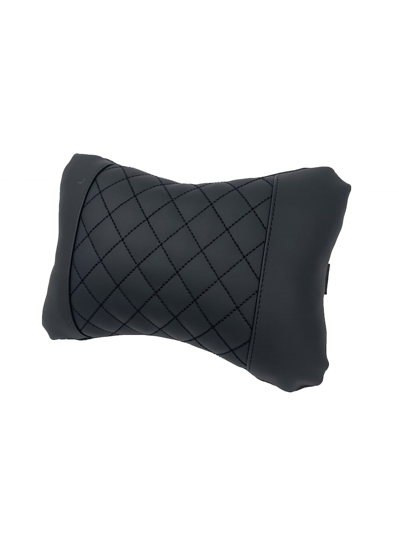 May include: Black quilted headrest pillow for car seats. The pillow is designed to provide comfort and support for the head and neck.
