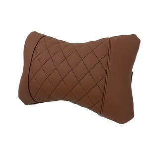 May include: A brown quilted neck pillow with a diamond pattern. The pillow is designed to provide support and comfort for the neck while traveling or sitting.