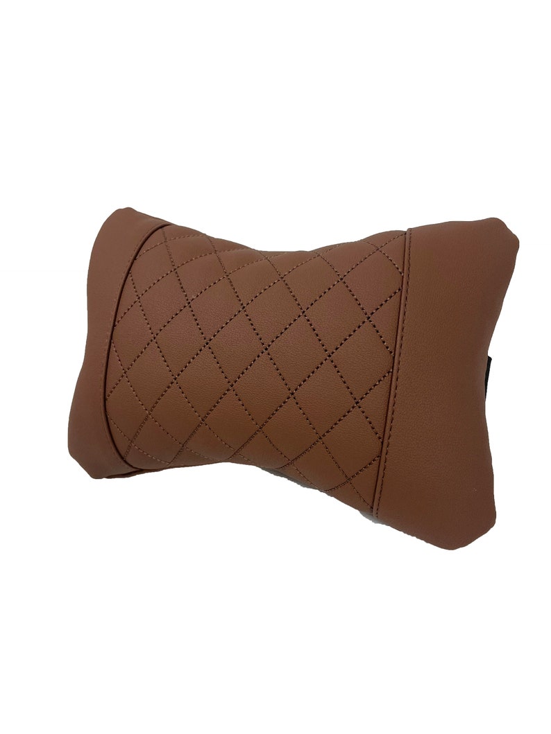 May include: A brown quilted neck pillow with a diamond pattern. The pillow is designed to provide support and comfort for the neck while traveling or sitting.