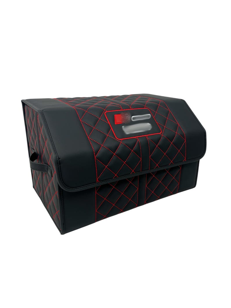May include: Black storage container with red diamond stitching. The container has a rectangular shape with a handle on the side. The top features a red and silver emblem.