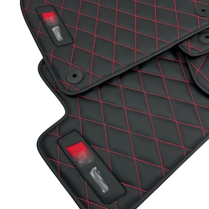 May include: Black car floor mats with red diamond stitching. The mats have a red accent on the driver's side mat.