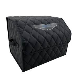 May include: Black quilted car organizer with a diamond pattern. Features a clear emblem on the front. Includes a handle on the side for easy carrying. The organizer is designed to keep items secure and organized.