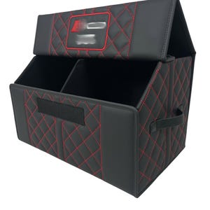 May include: Black car organizer with red diamond stitching. The organizer has a divided interior, a handle, and a lid. The lid features a red-outlined emblem. The organizer is designed to keep a car's interior tidy.
