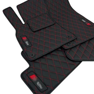 May include: Set of four black car floor mats with red diamond stitching. The mats are made of a durable material and are designed to protect your car's interior.