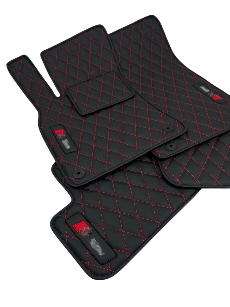 May include: Set of four black car floor mats with red diamond stitching. The mats are made of a durable material and are designed to protect your car's interior.