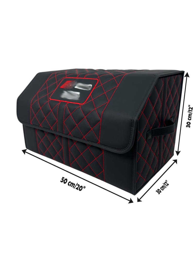 May include: Black car trunk organizer with red stitching. The organizer is 20 inches long and 12 inches high. It features a quilted pattern and a logo on the lid. Includes a handle for easy carrying.