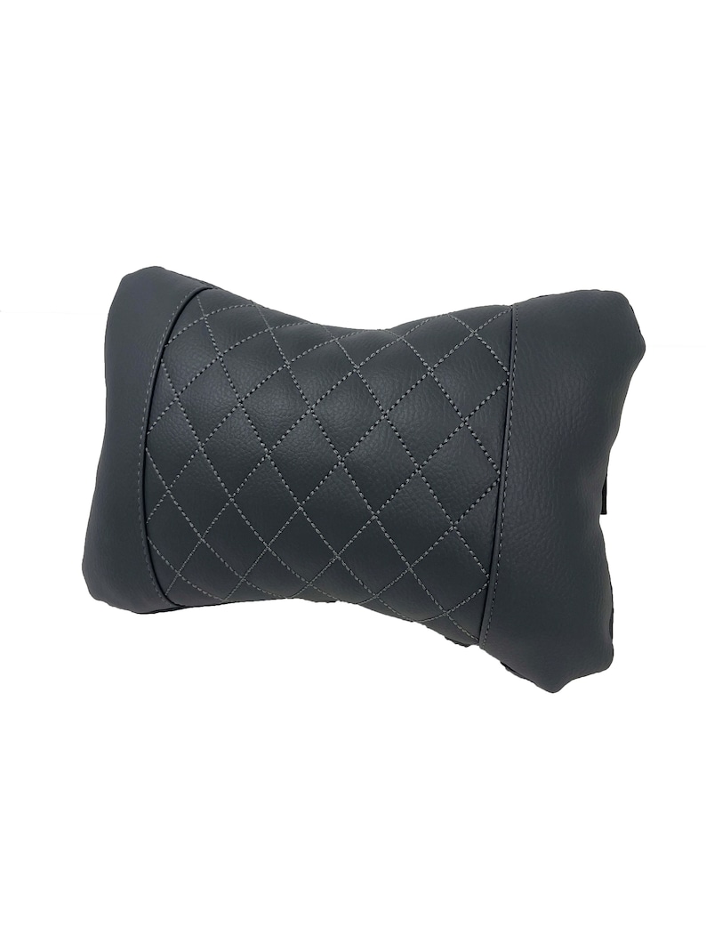May include: A gray quilted neck pillow with a diamond pattern. The pillow is designed to provide support and comfort for the neck while sitting or driving.