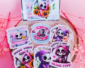 May include: A set of six stickers featuring a cartoon Grim Reaper in various poses with different phrases. The stickers are printed on white paper with a glossy finish. The phrases on the stickers include "Coffee is my blood type", "Good vibes only", "Duck you", "Donut disturb", "I love plants", and "Duck off!"
