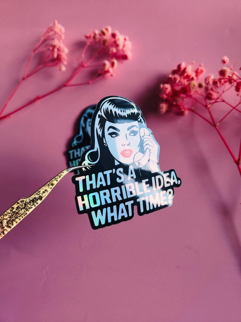 May include: A sticker featuring a retro-style illustration of a woman holding a telephone. The sticker has the text "THAT'S A HORRIBLE IDEA, WHAT TIME?" in white. The sticker has a holographic effect and is held by tweezers.