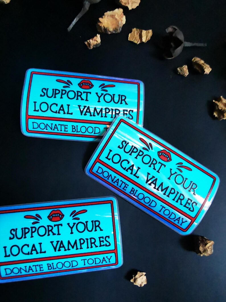 Może przedstawiać: Trzy niebieskie i czerwone naklejki z tekstem "Support Your Local Vampires" i "Donate Blood Today".