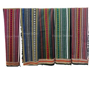 Könnte beinhalten: Fünf verschiedene gemusterte Stoffstreifen mit schwarzen, roten, blauen, grünen und weißen Streifen. Der Stoff hat eine gewebte Textur und wird wahrscheinlich für Kleidung oder Wohnaccessoires verwendet.