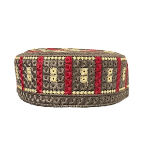 Peut inclure: Un calot brodé marron avec des motifs géométriques rouges et jaunes. Le bonnet présente un design détaillé avec des rayures rouges verticales et des formes florales jaunes, créant un aspect texturé. Les bords sont finis avec une bordure décorative.