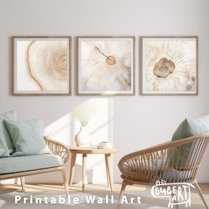 May include: Three square prints of wood grain with a light brown and beige color scheme. The prints are framed in a light wood frame and hung on a white wall. The prints are arranged in a row, with the middle print slightly higher than the other two. The prints are in a living room setting with a couch and a chair in the foreground.