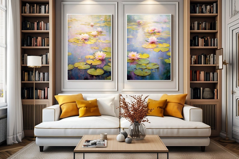 May include: Two framed paintings of pink water lilies on a pond with green lily pads. The paintings are hanging on a wall above a white couch with yellow throw pillows. There is a vase with dried flowers on a wooden coffee table in front of the couch.