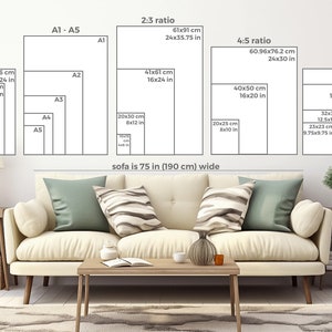 May include: A white sofa with two pillows, a coffee table, and a side table with a lamp and a vase. The wall behind the sofa has a diagram showing different paper sizes and their dimensions in inches and centimeters. The text on the wall reads "sofa is 75 in (190 cm) wide".