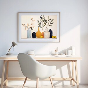 May include: A framed print of a still life featuring a collection of vases with a yellow vase in the center, a leafy branch, and lemons. The print is hanging on a white wall above a desk with a lamp, a laptop, and a chair.