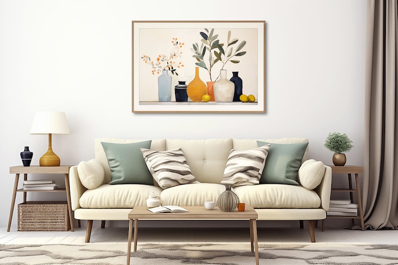 May include: A framed watercolor painting of a still life with a variety of vases and branches with yellow flowers and green leaves. The vases are in shades of blue, black, yellow, and white. The painting is hanging on a white wall above a white couch with green and striped pillows.