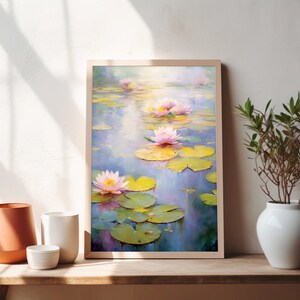 May include: A framed painting of pink water lilies with green lily pads floating on a blue pond. The painting is in a light wood frame and is hanging on a white wall.