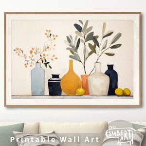 A printable of a still life featuring a vase of olive branches and ceramic vases in shades of blue, yellow, white, and black. The vases are arranged on a table with lemons in front of them.