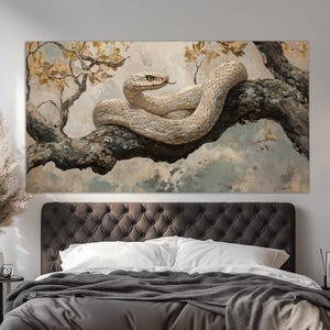 Op de afbeelding: Een canvas print met een gedetailleerde schildering van een slang die op een tak ligt. De slang is licht van kleur met een textuurpatroon en de tak is donkerbruin. De achtergrond heeft een zacht, wolkig effect met hints van goud.