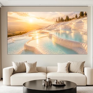 Op de afbeelding: Een grote rechthoekige wandprint met een zonsondergang boven de witte travertijnterrassen en turquoise thermale baden van Pamukkale, Turkije, met cipressen langs de bergkam en een gouden zon die boven de verre horizon schijnt.