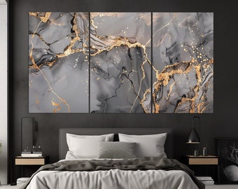 Könnte beinhalten: Ein dreiteiliges abstraktes Kunst-Druckset mit einem grauen und goldenen Marmormuster. Die Drucke werden an einer Wand über einem grauen, gepolsterten Bett mit weißen Bettwäsche präsentiert.