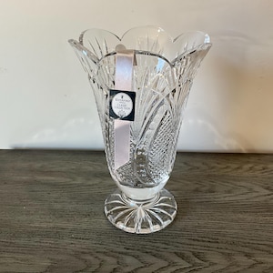 Puede incluir: Un jarrón de cristal transparente de la colección Waterford Classic. El jarrón tiene un borde acampanado y festoneado y complejos patrones de vidrio tallado. Se asienta sobre una base redonda y estampada e incluye una cinta blanca.