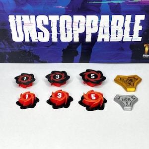 May include: A set of six red and black plastic game pieces with white numbers 1, 3, and 5. There are also two gold and silver metal game pieces with a design on them. The game pieces are on a white surface. The game is called "Unstoppable".