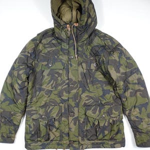 May include: A green and brown camouflage hooded jacket with a button front and two large flap pockets. The jacket has a drawstring hood and a quilted lining.