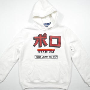May include: White hooded sweatshirt with a red and black graphic that says "ポロ STADIUM Ralph Lauren est. 1967"