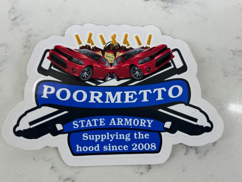 May include: A white sticker with a blue banner that says "POORMETTO STATE ARMORY Supplying the hood since 2008". The banner is flanked by two red Dodge Charger cars with gold bottles on top.