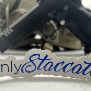 May include: A white sticker with blue text that reads "Only Staccatos" with a star in a circle on the left side.