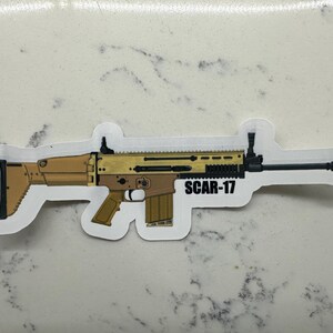 May include: A sticker of a tan and black SCAR-17 rifle with the text "SCAR-17" printed on the sticker.
